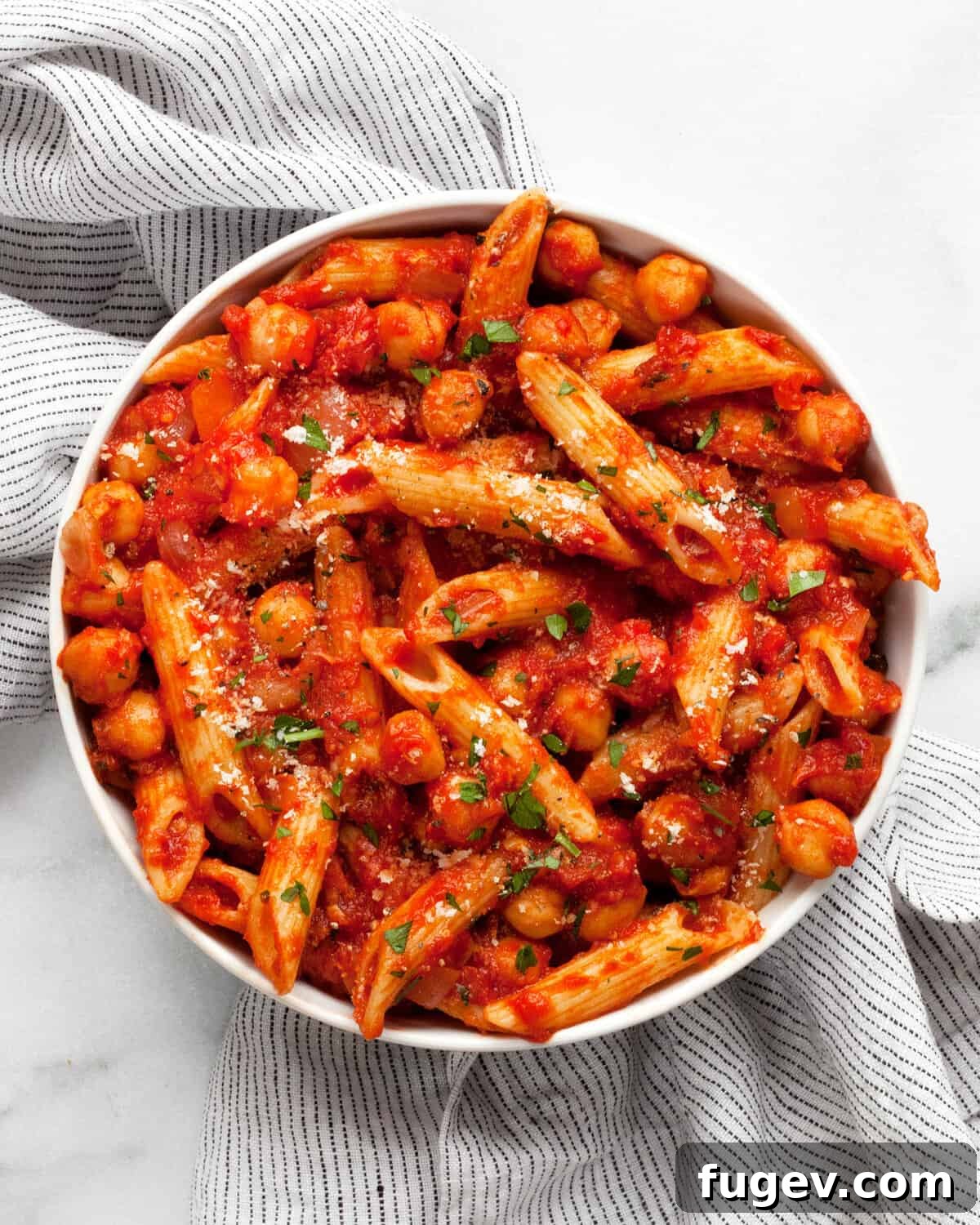 Arrabbiata Penne with a Chickpea Twist 2 A small bowl filled with spicy Penne Arrabbiata featuring tender chickpeas and a vibrant red sauce, garnished with fresh herbs.