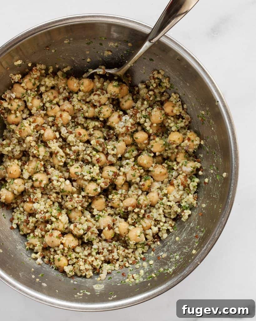 Hearty Acorn Squash and Chickpea Quinoa 7 Mixing cooked quinoa, chickpeas, and pesto in a large bowl