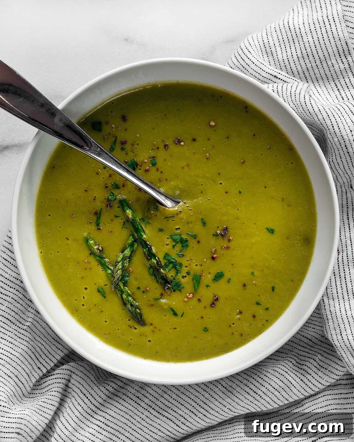 Silky Roasted Asparagus Soup 8 A bowl of vibrant green asparagus soup, garnished beautifully.