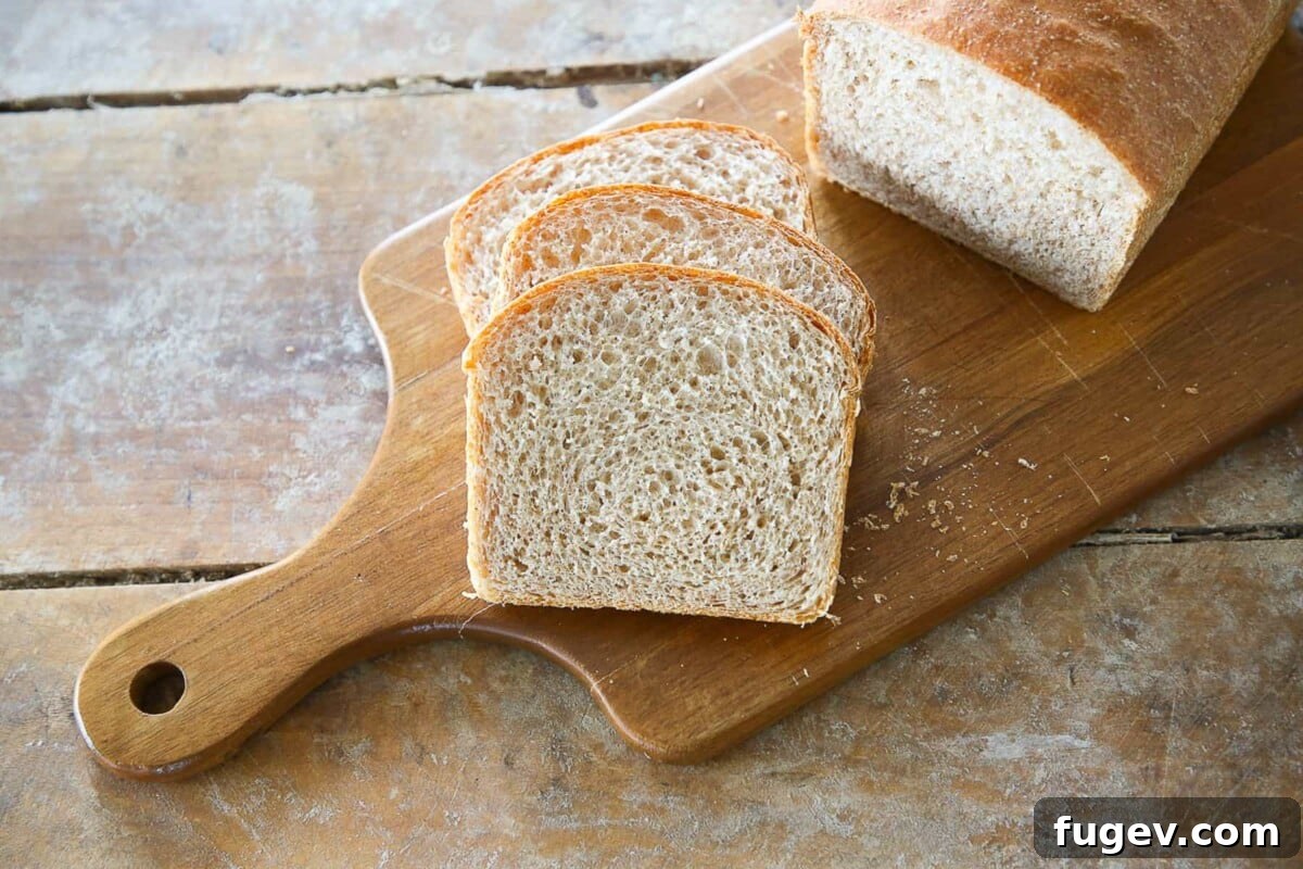 Hearty Homemade Whole Wheat Bread 3 A whole wheat sandwich loaf sliced on a wooden cutting board.