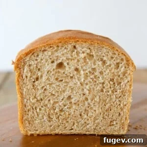 A partially cut loaf of whole wheat sandwich bread, showing a soft inside.