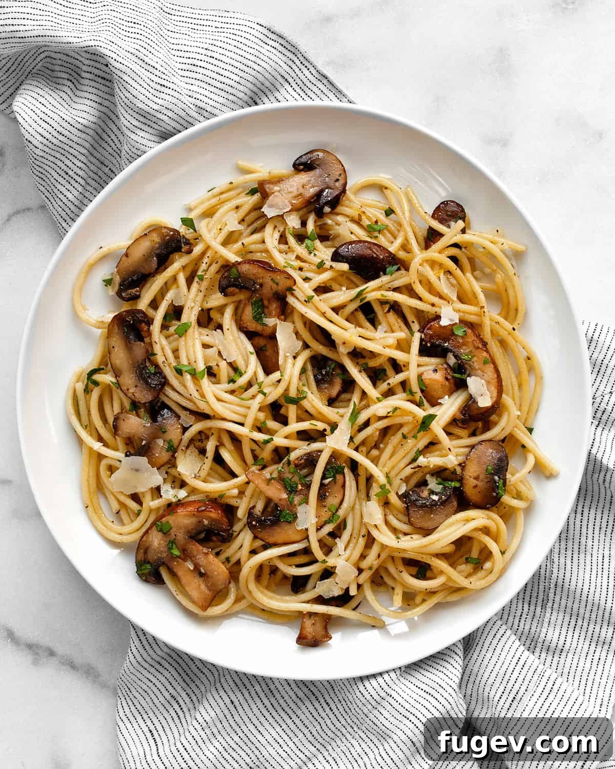 Lemon-Kissed Garlic Mushroom Pasta 8 A close-up shot of lemon garlic mushroom spaghetti served on a white plate, garnished with fresh parsley.
