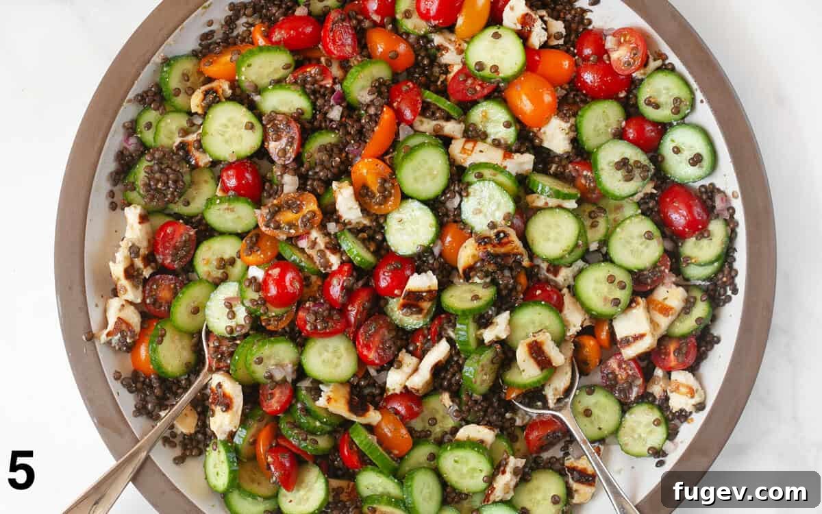 Mediterranean Grilled Halloumi Lentil Salad 6 A large salad bowl filled with the finished grilled halloumi and lentil salad, tossed with pesto vinaigrette, ready to be served.