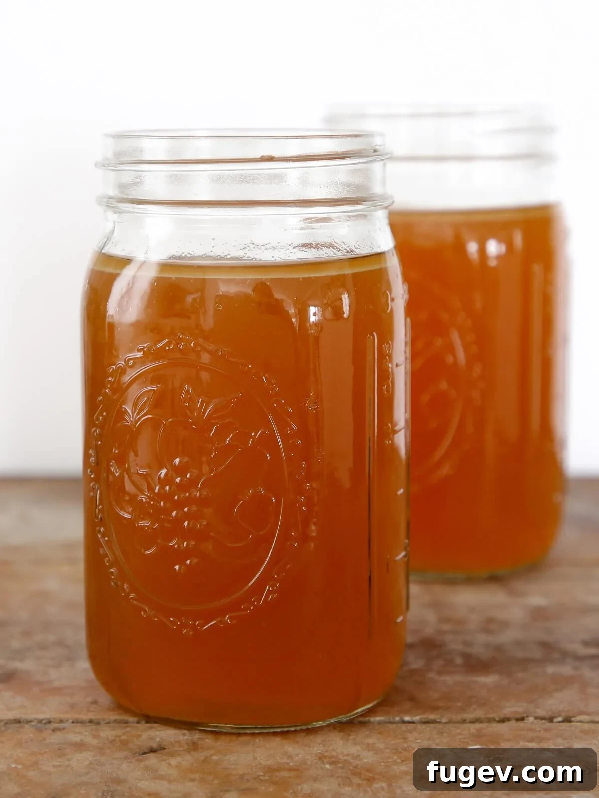 Mastering the Art of Golden Chicken Broth 2 Two mason jars filled with golden homemade chicken broth, ready for use or storage.