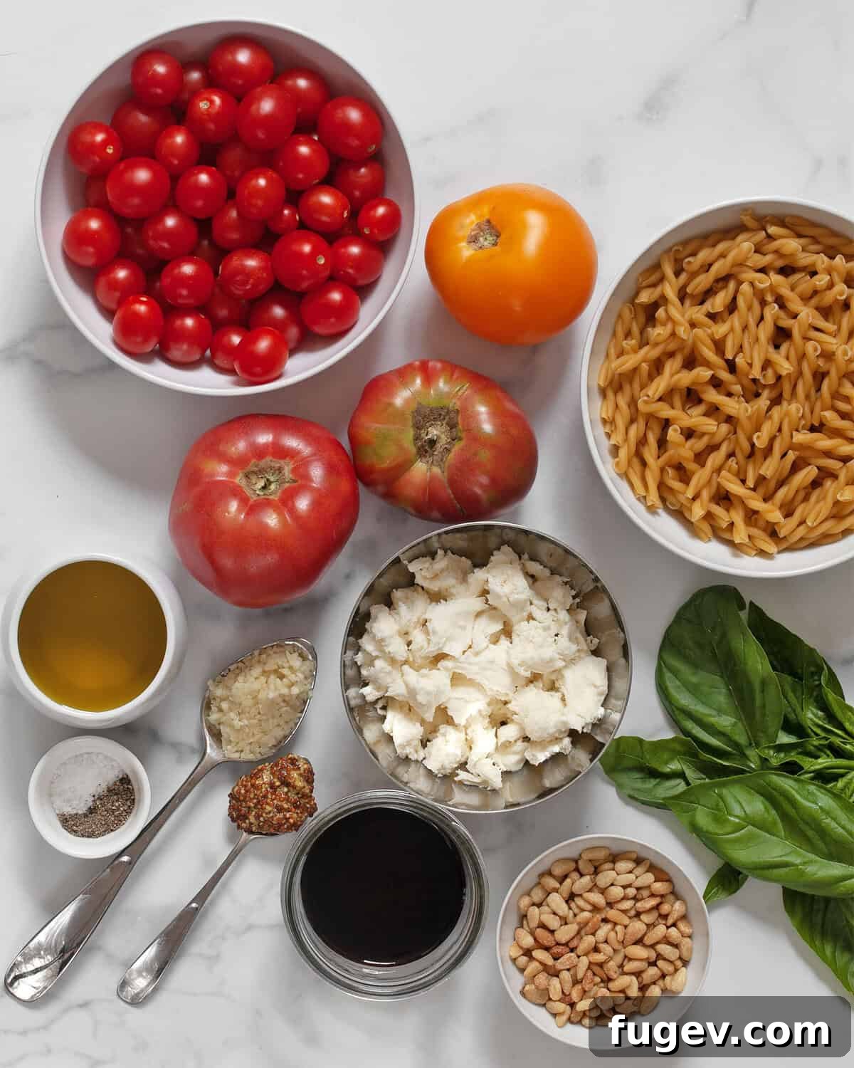 Bruschetta Inspired Pasta Salad 3 A vibrant selection of fresh ingredients laid out for bruschetta pasta salad, including assorted tomatoes, dry pasta, fresh mozzarella, basil, garlic, olive oil, and balsamic vinegar.