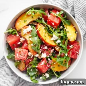 Watermelon Peach Bliss 6 Watermelon salad with peaches, feta, arugula and jalapeño lime dressing in a bowl, ready to serve.