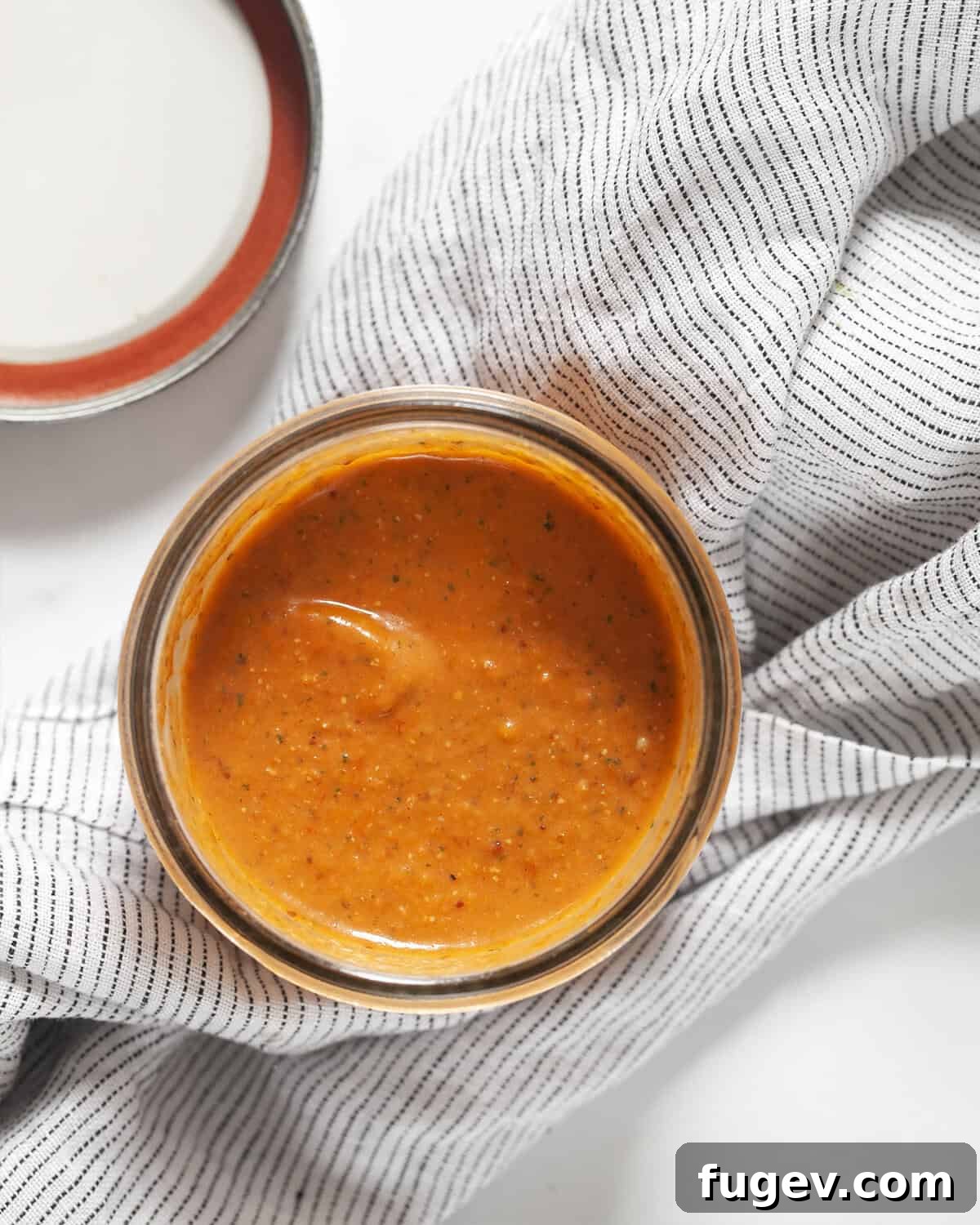 Golden Harvest Roasted Tomato Dressing 6 A charming mason jar filled with the vibrant homemade roasted tomato vinaigrette, sitting on a rustic wooden surface, ready for storage or immediate serving. The rich red color of the dressing is prominently displayed.