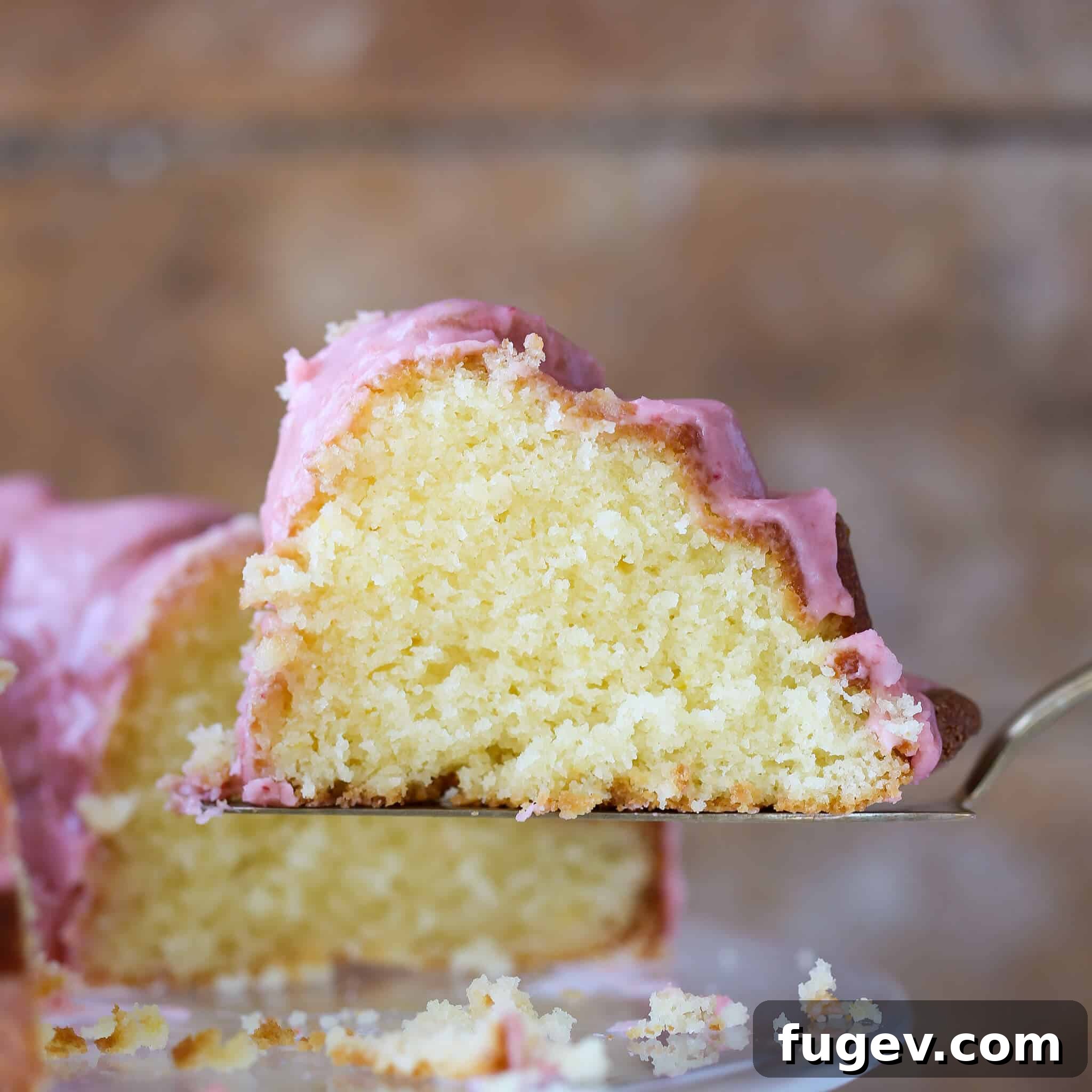Zesty Lemon Loaf 9 A perfectly sliced Lemon Pound Cake with strawberry icing, showcasing the moist interior and vibrant glaze from the side.