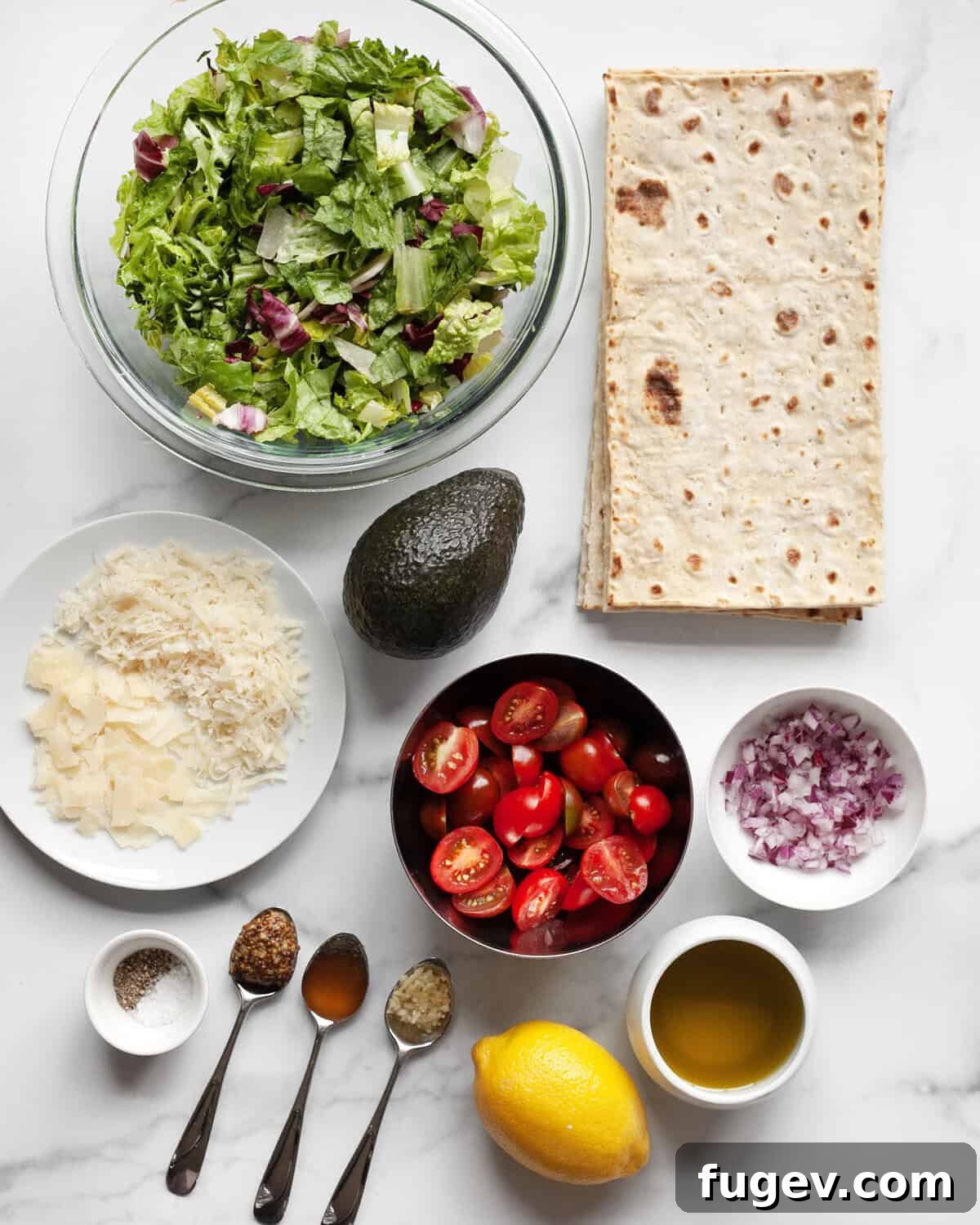 Crispy Lavash Garden Flatbread 3 All the fresh ingredients laid out for mixed greens salad pizza, including lavash bread, various salad greens, Parmesan cheese, sliced avocado, halved cherry tomatoes, finely diced red onions, a fresh lemon, honey, Dijon mustard, minced garlic, salt, and pepper.
