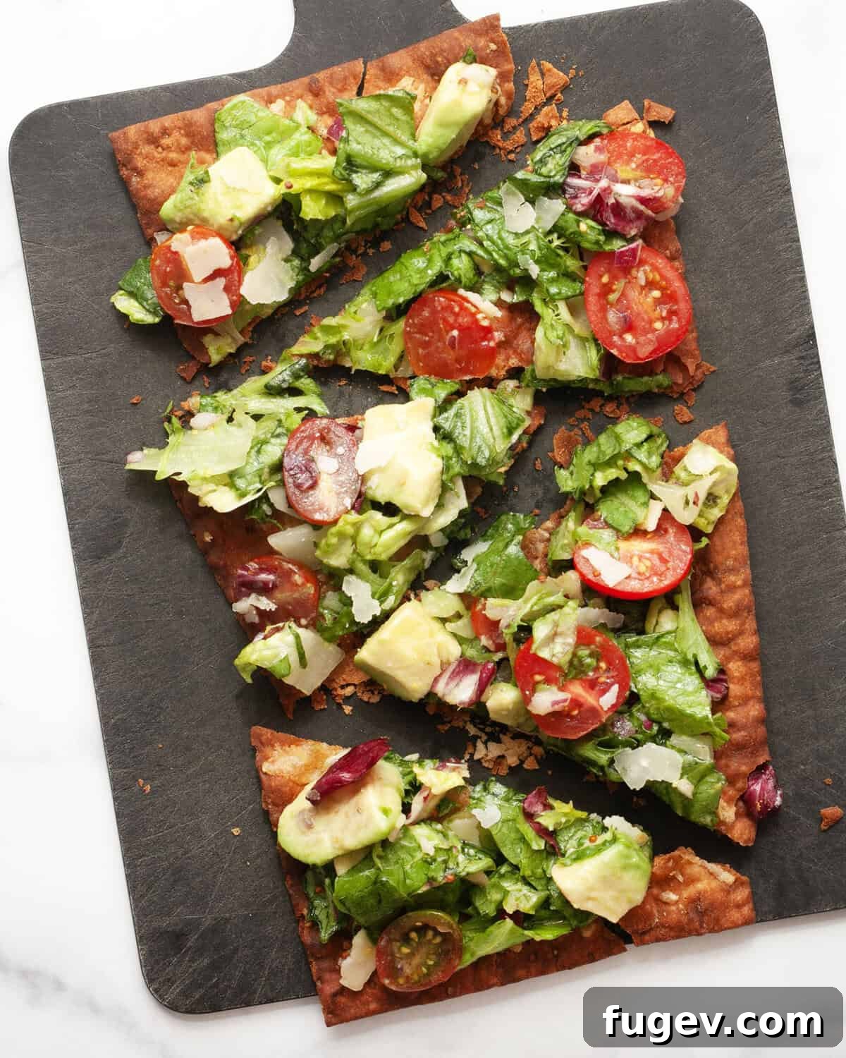 Crispy Lavash Garden Flatbread 7 A freshly made mixed greens salad pizza, beautifully cut into individual slices, showcasing the vibrant green toppings and crispy golden crust.