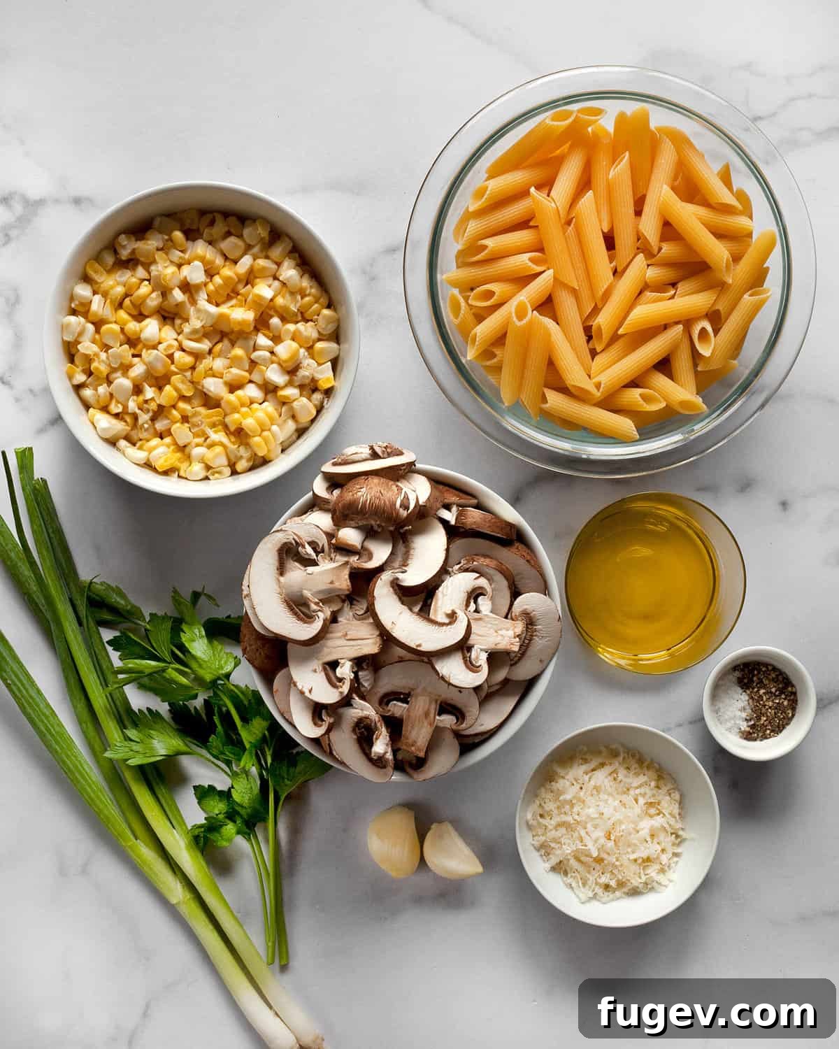 Savory Mushroom Sweet Corn Pasta 3 Key ingredients for mushroom corn pasta, including cremini mushrooms, sweet corn, penne pasta, garlic, scallions, Parmesan cheese, and fresh parsley.