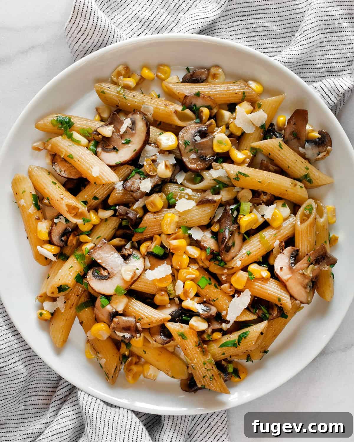 Savory Mushroom Sweet Corn Pasta 7 A serving of mushroom corn pasta on a white plate, garnished with fresh herbs.