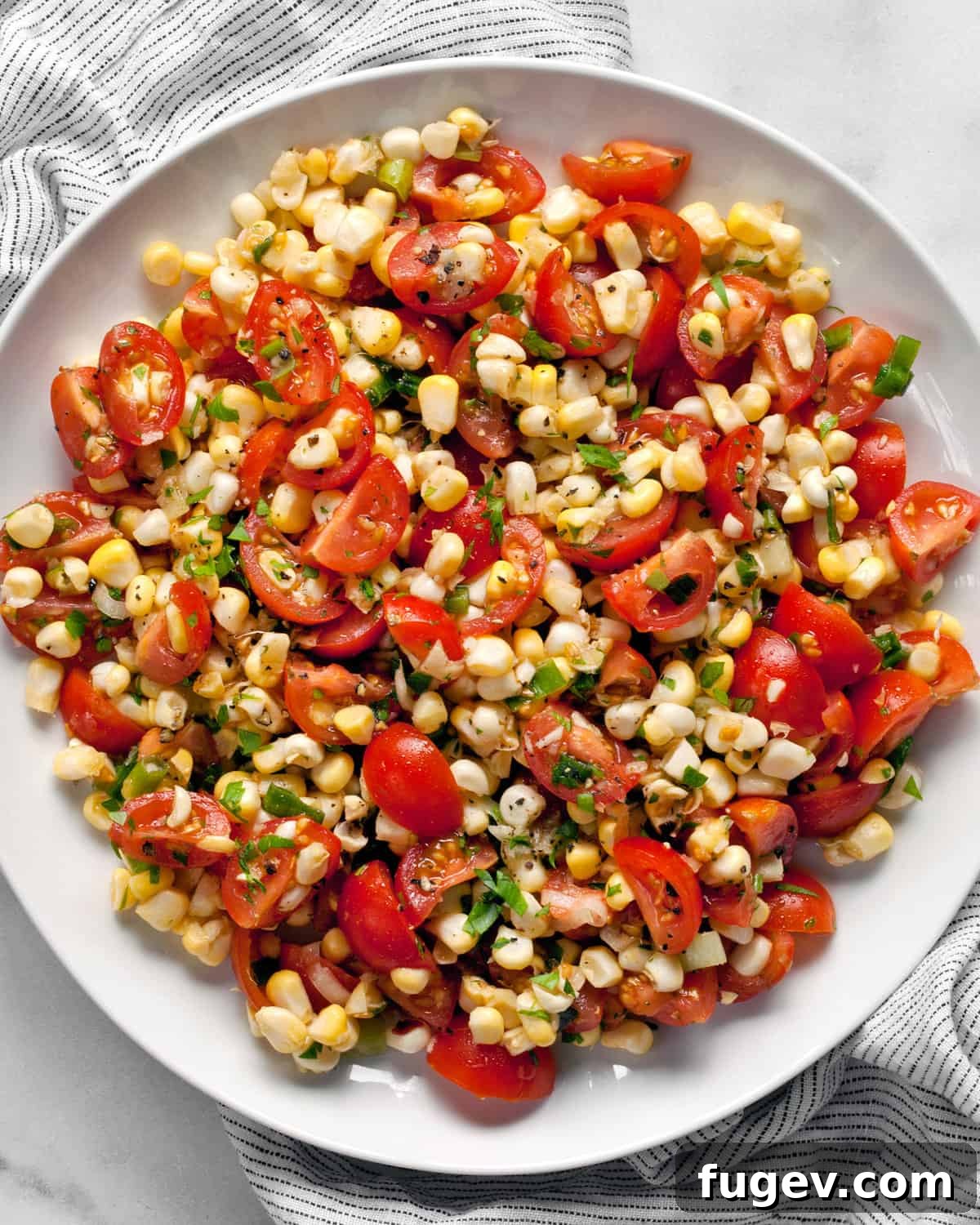 Vibrant Summer Corn and Tomato Salad 5 A close-up shot of the fresh corn and tomato salad served on a white plate, showcasing the juicy kernels and bright red tomatoes.