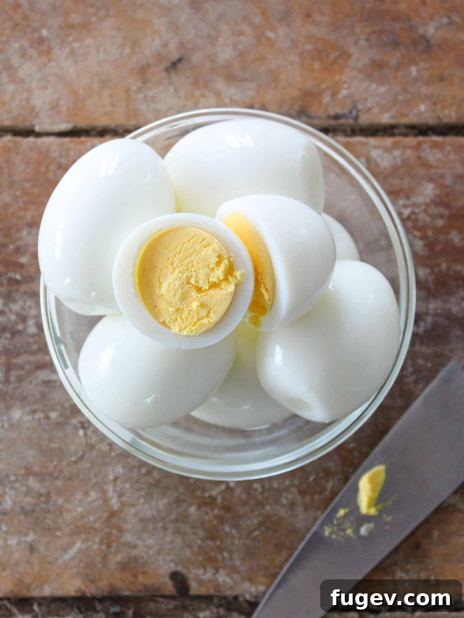 Achieving Perfect Hard Boiled Eggs 3 Two perfectly hard-boiled eggs in a bowl on a wooden surface