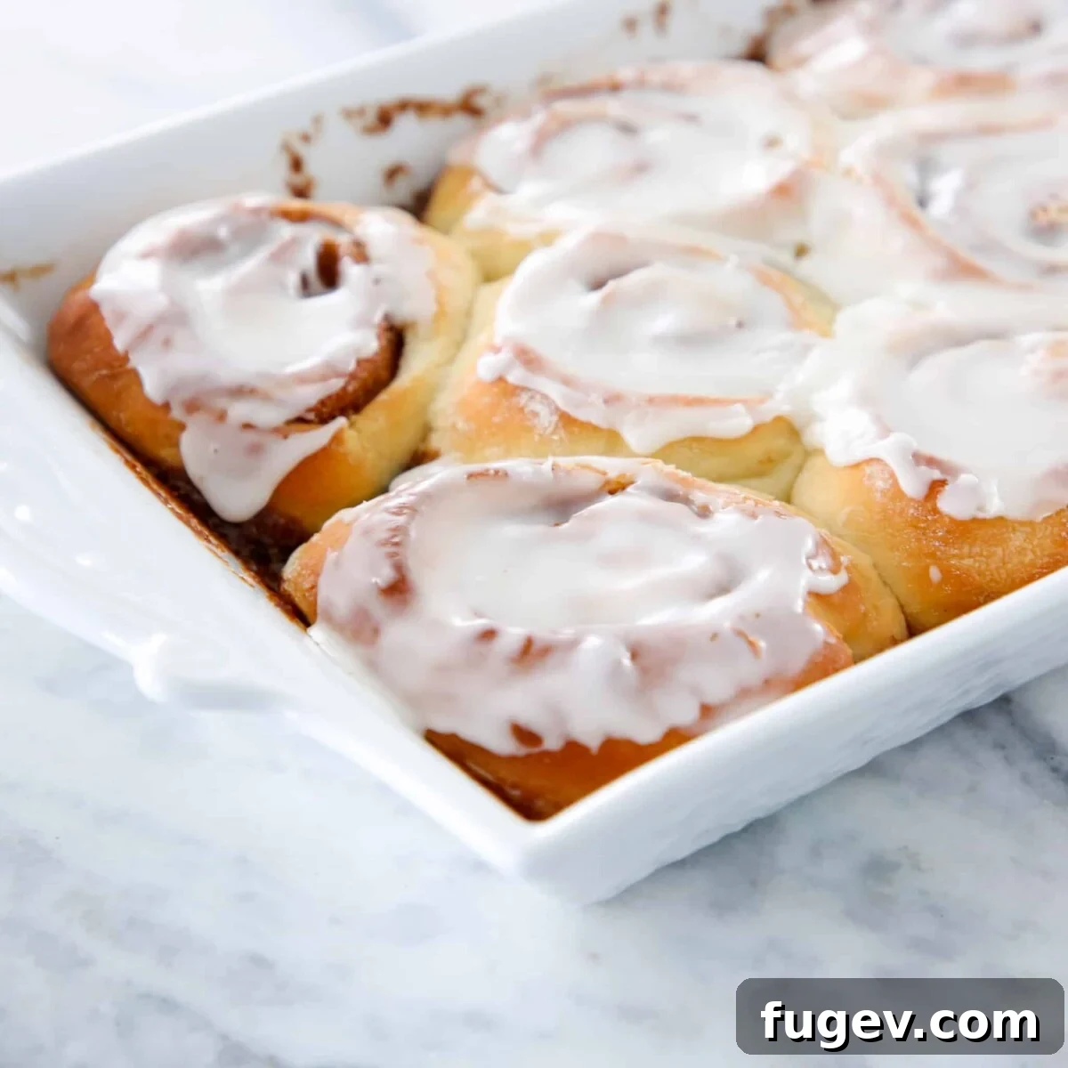 Fluffy Sourdough Cinnamon Rolls 5 Freshly baked sourdough cinnamon rolls topped with a generous layer of white icing, meticulously arranged and ready to be served for a delightful breakfast or dessert.