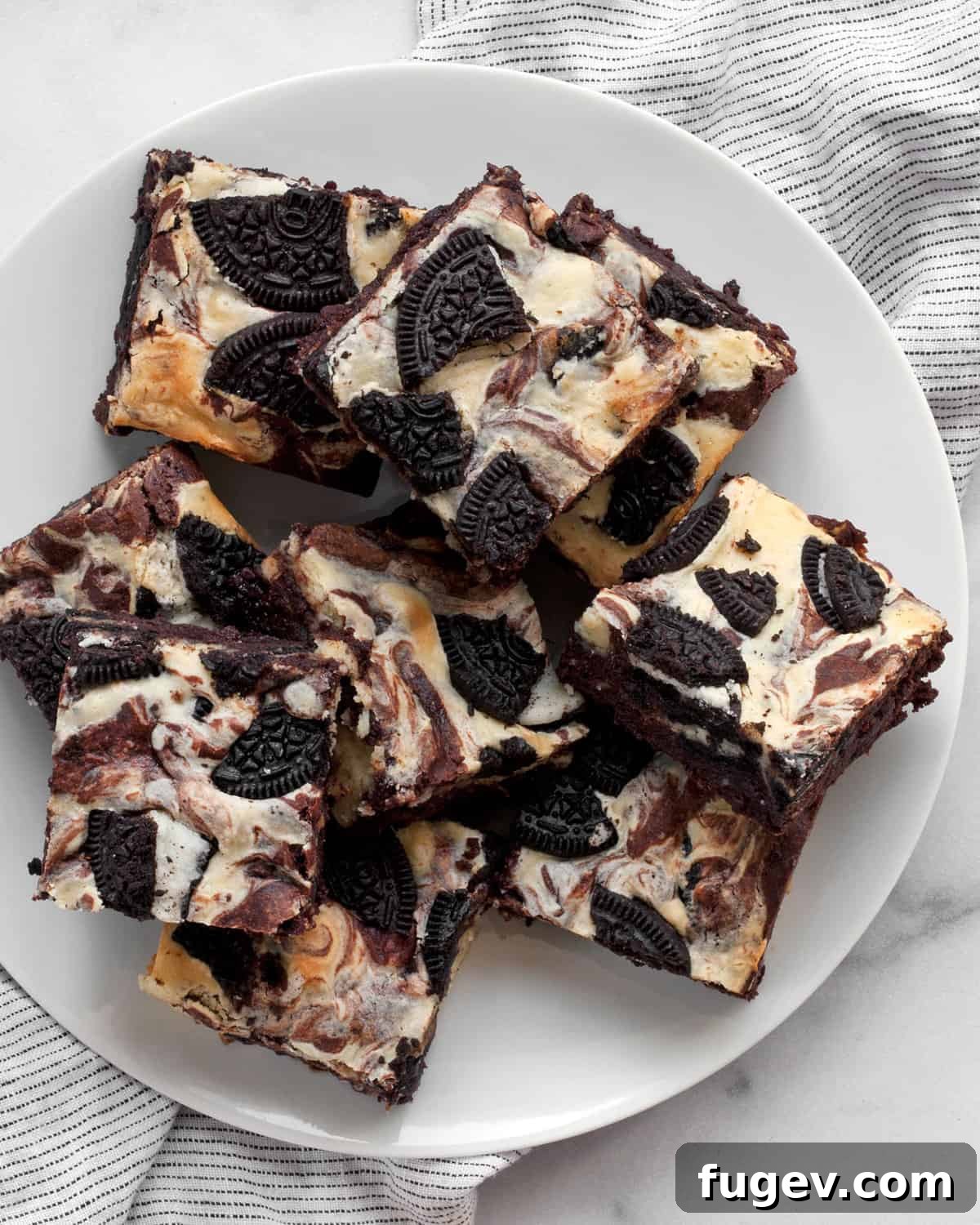 Swirled Cream Cheese Brownies 8 A perfectly cut cream cheese brownie square, showcasing the beautiful cheesecake swirl and Oreo pieces, served on a white plate.
