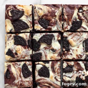 Swirled Cream Cheese Brownies 9 Rows of perfectly cut cheesecake brownies with visible swirls and Oreo pieces.