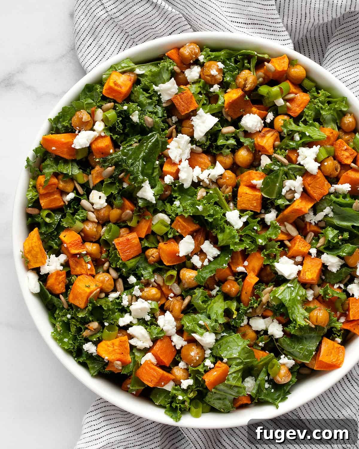 Roasted Sweet Potato & Kale Harvest Bowl 6 A close-up of a rustic bowl filled with vibrant kale salad, perfectly roasted sweet potatoes, and crispy chickpeas, ready to be enjoyed.
