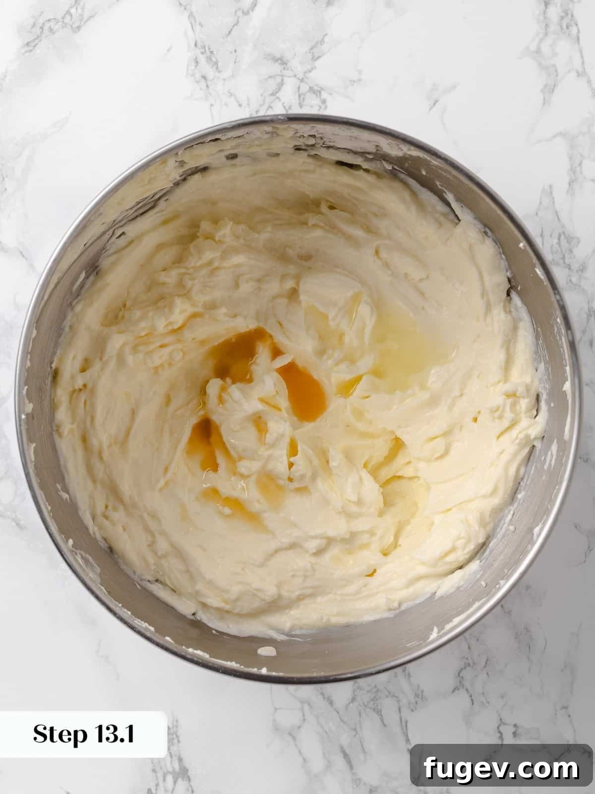 Irresistible Homemade Carrot Cake 20 Vanilla extract being poured into the mixing bowl of cream cheese frosting, adding a touch of aromatic flavor.