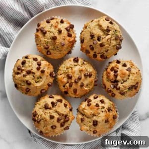 Seven chocolate chip zucchini muffins on a plate.