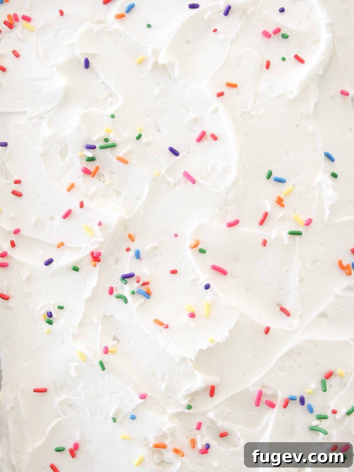 Sunshine Lemon Cloud Frosting 8 Swirled lemon buttercream frosting with colorful sprinkles on a cake.