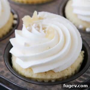 piped lemon buttercream frosting on cupcakes in a baking tin.