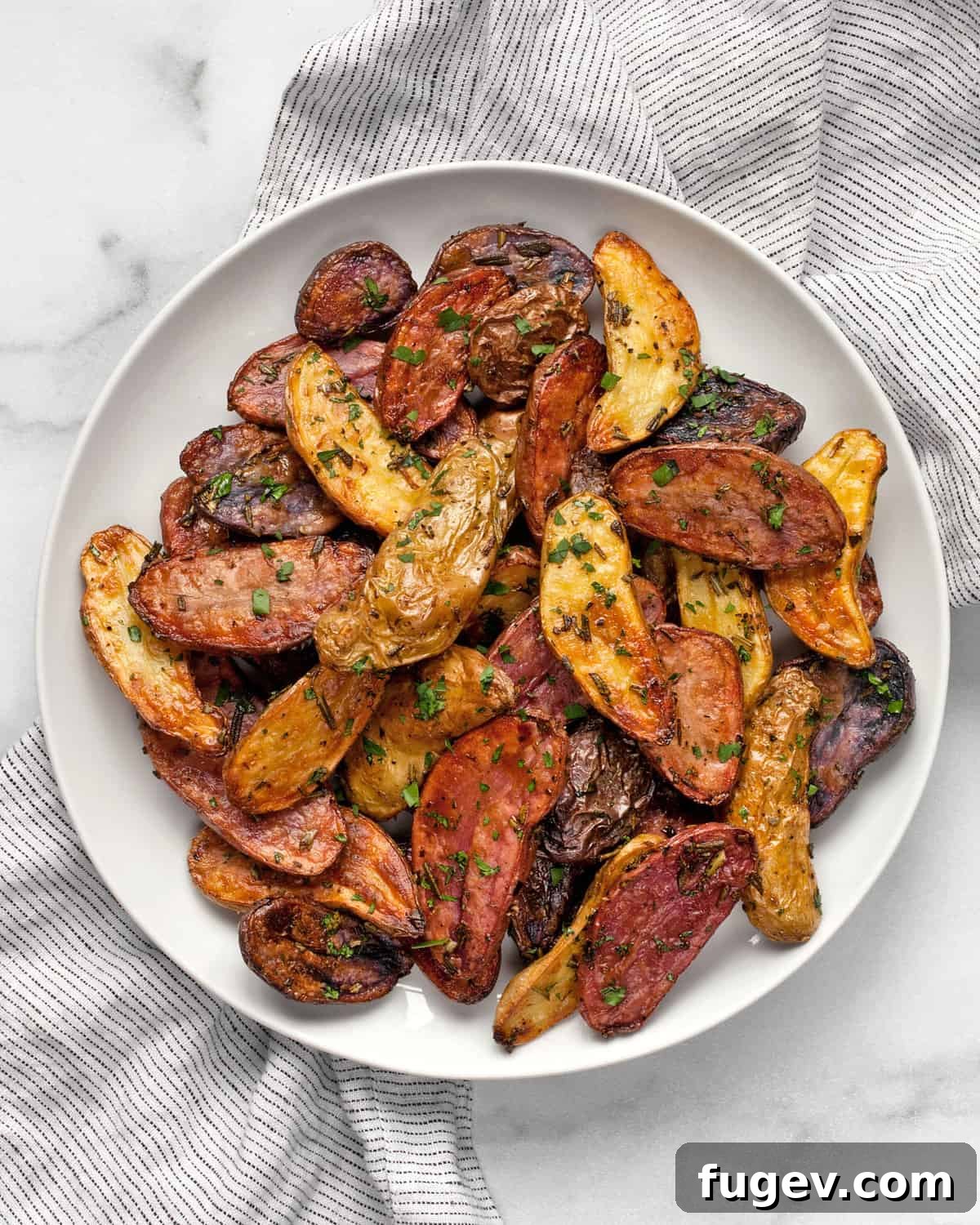 Lemon Rosemary Roasted Potatoes A serving of golden, crispy lemon rosemary roasted potatoes garnished with fresh herbs on a white plate, ready to be enjoyed.