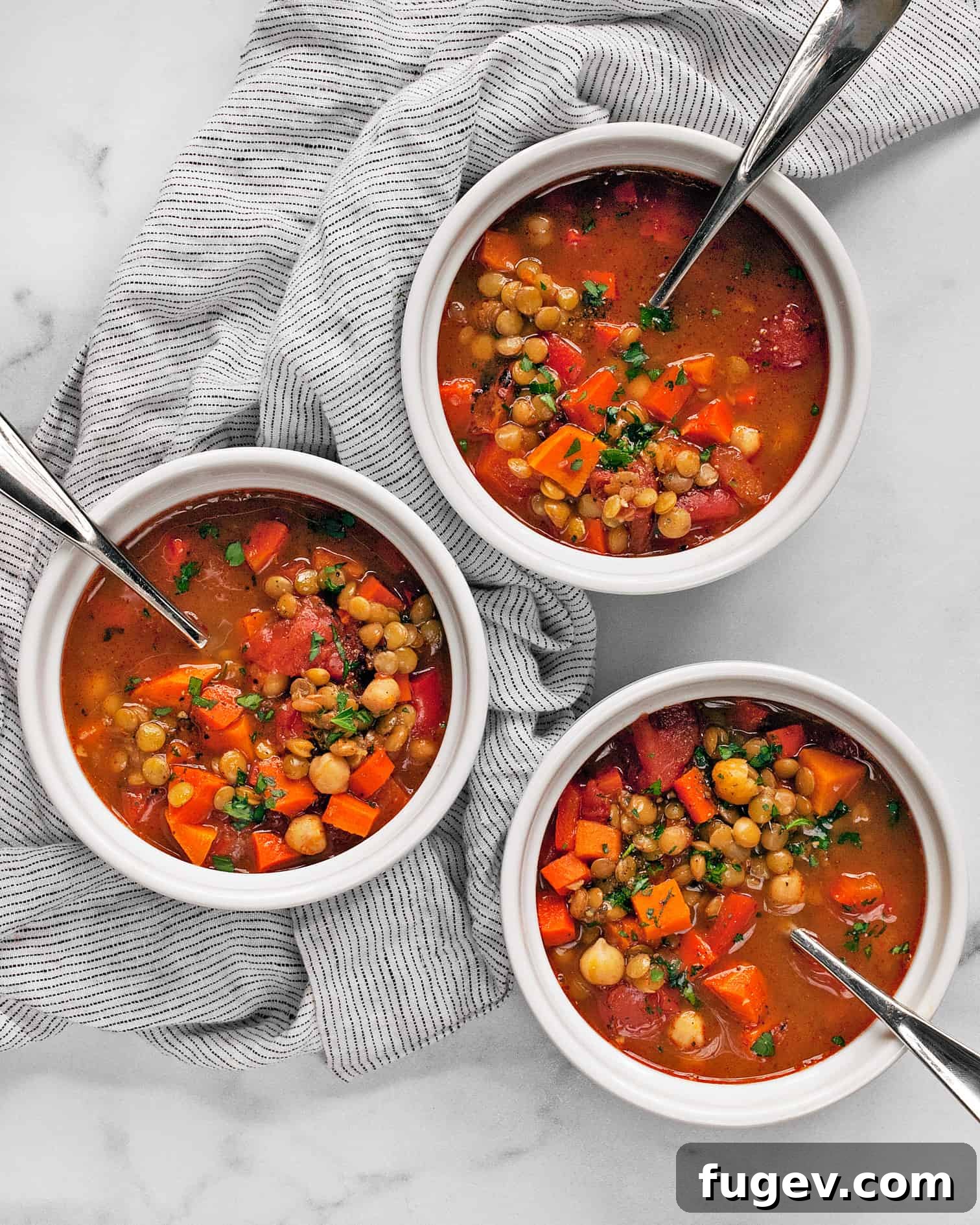 Spiced Slow Cooker Moroccan Chickpea Stew 2 A vibrant bowl of vegan slow cooker Moroccan chickpea stew, rich with sweet potatoes, carrots, red peppers, and green lentils, garnished with fresh parsley.
