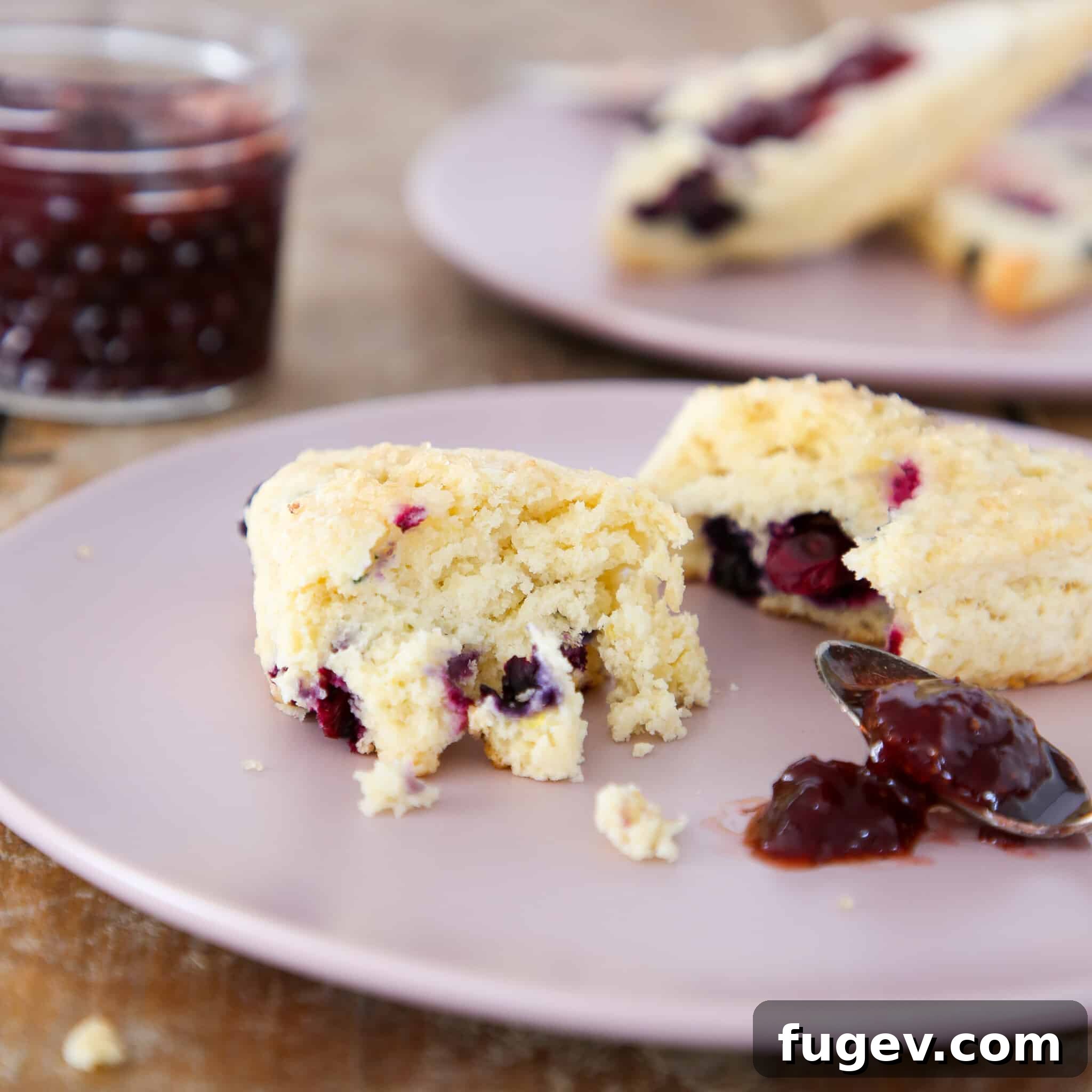 Bursting Blueberry Scones 2 Perfectly baked blueberry scones, golden brown and glistening with sugar, on a cooling rack.