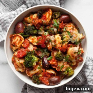 Tortellini pasta bake served in a bowl, garnished with fresh herbs.