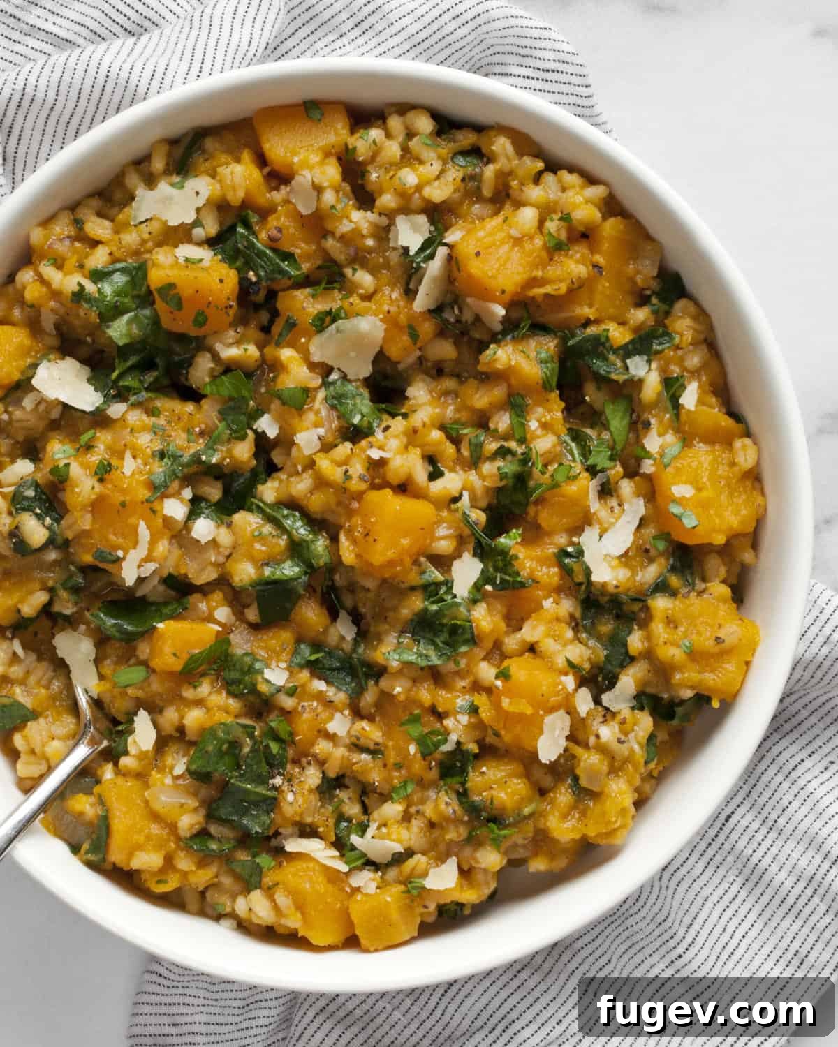 Velvety Baked Butternut Risotto 2 A bowl of creamy baked butternut squash and barley risotto, garnished with fresh herbs and a sprinkle of cheese.