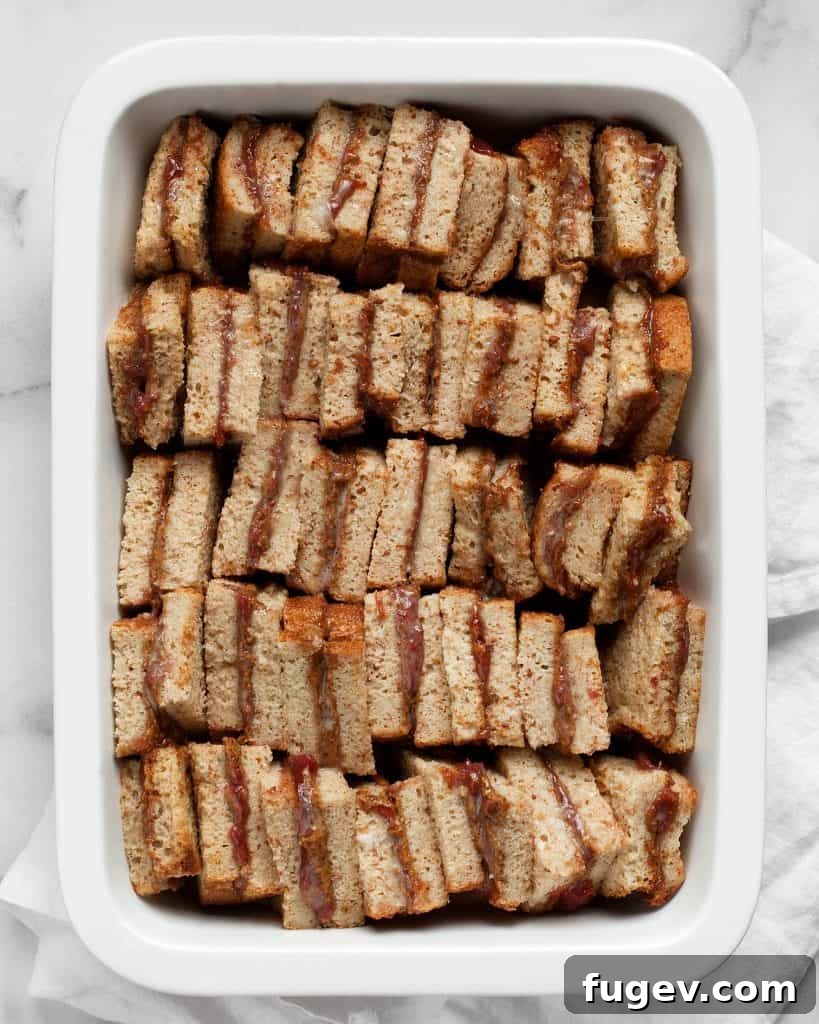 Almond Butter & Jelly French Toast Bake 4 Assembling mini almond butter and jelly sandwiches in a baking dish