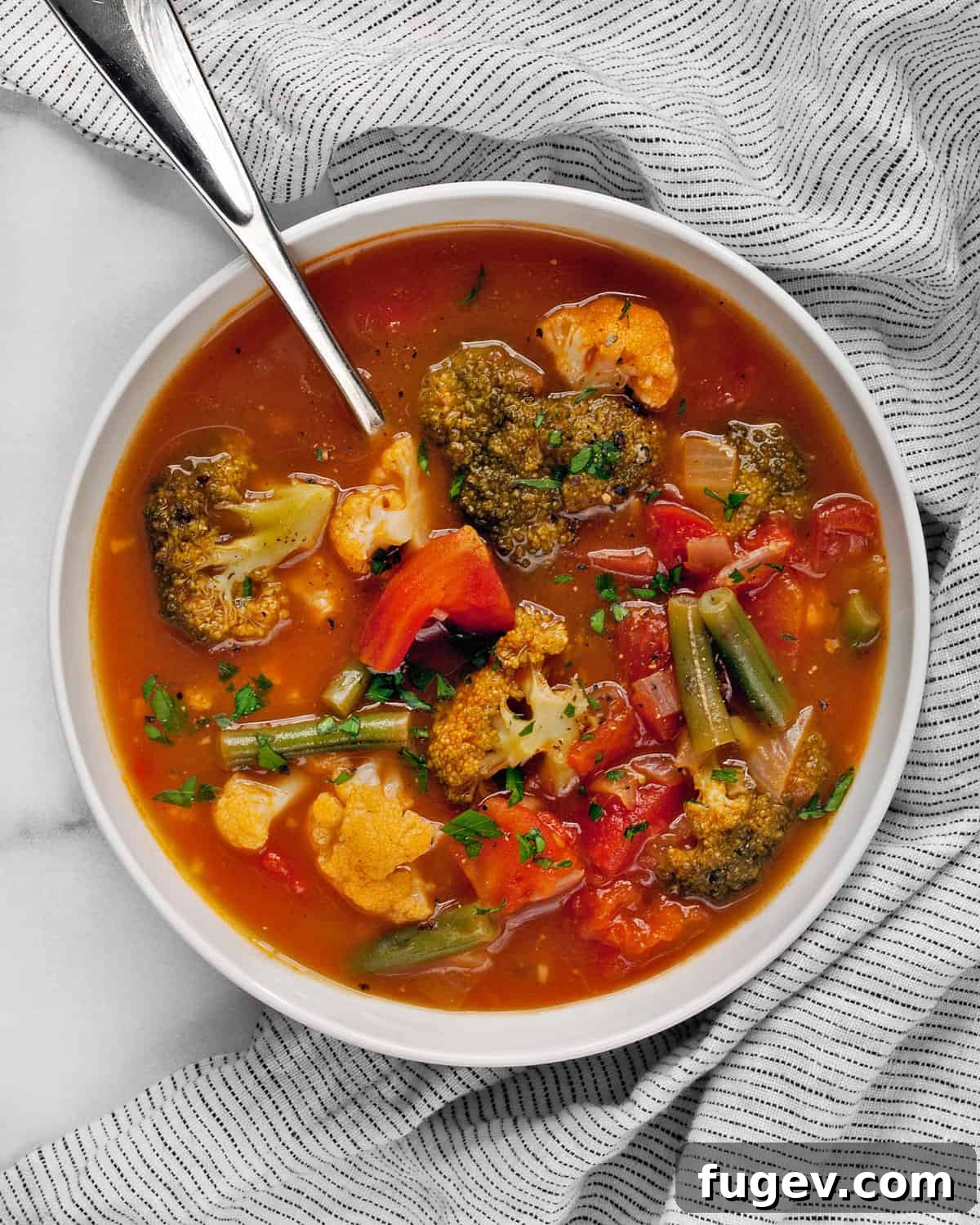 Comforting Harvest Vegetable Soup 7 A close-up of a rustic bowl filled with hearty vegetable soup, showcasing chunky pieces of tomatoes, tender cauliflower, and vibrant broccoli, ready to be enjoyed.