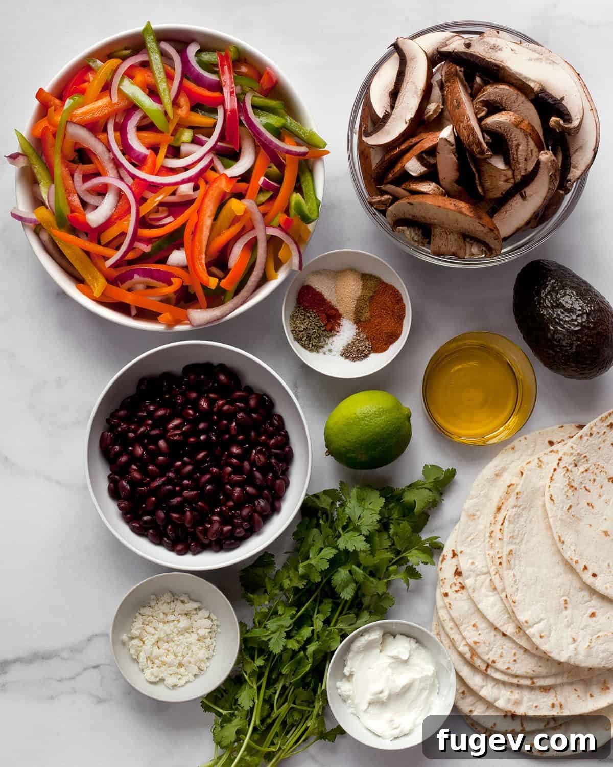 Sheet Pan Veggie Fajita Fiesta 3 Ingredients including, bell peppers, onion, portobello mushrooms, black beans, cilantro, lime, tortillas and cheese, artfully arranged on a kitchen counter.