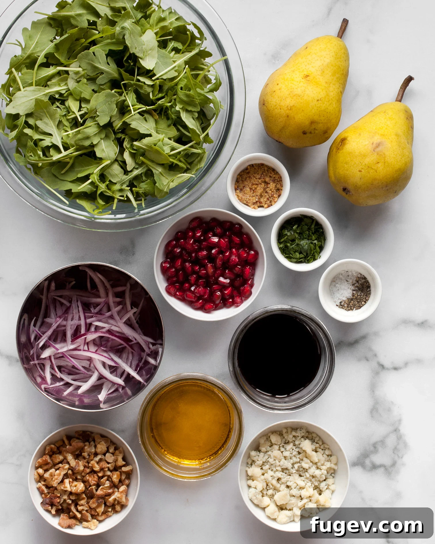 Juicy Pear and Creamy Gorgonzola Salad 3 A selection of fresh ingredients for Pear Gorgonzola Salad, including vibrant arugula, ripe pears, thinly sliced red onions, walnuts, pomegranate seeds, balsamic vinegar, olive oil, and crumbled Gorgonzola cheese.