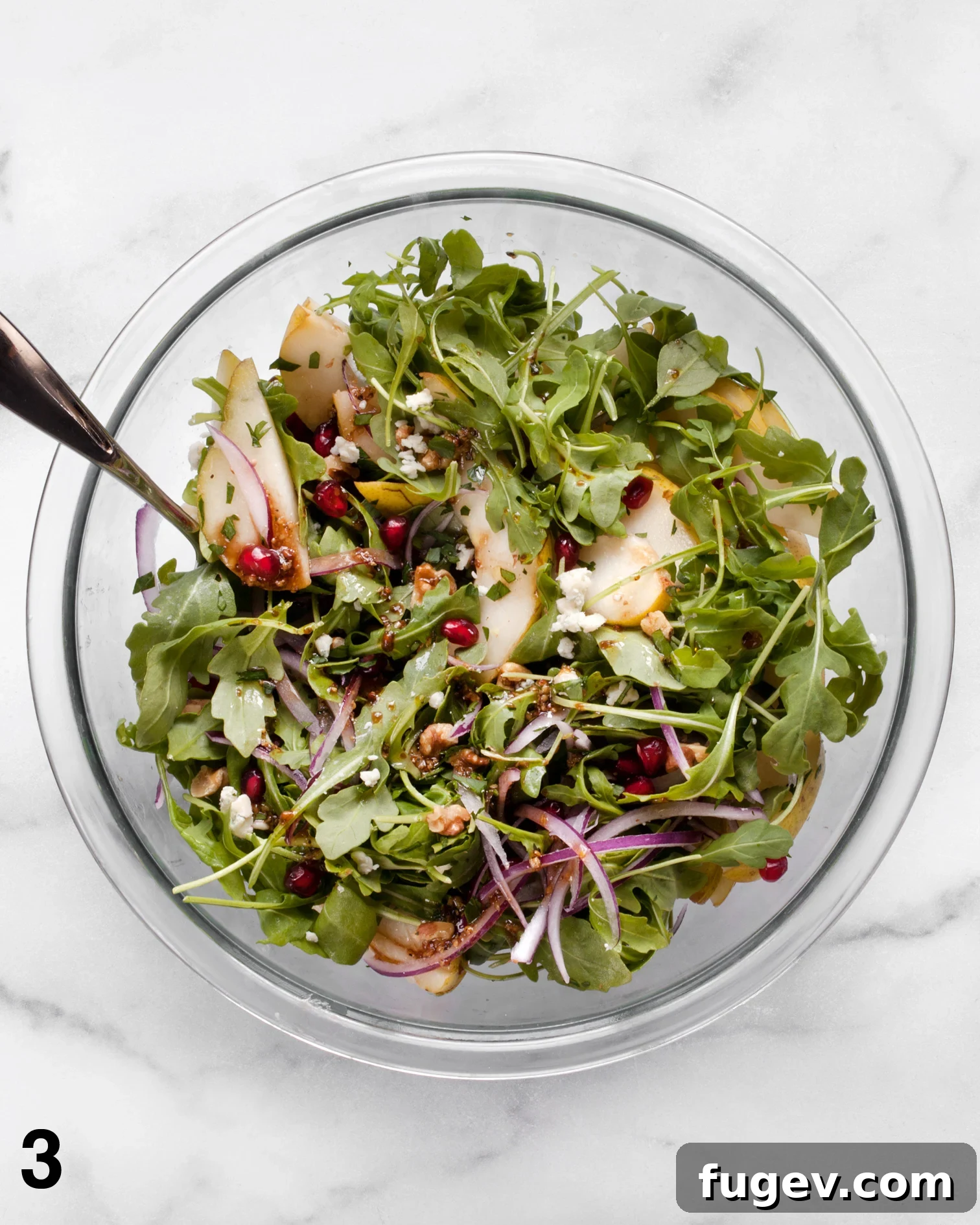 Juicy Pear and Creamy Gorgonzola Salad 5 A large bowl of Pear Gorgonzola Salad being gently tossed with balsamic vinaigrette, ensuring all ingredients are evenly coated.