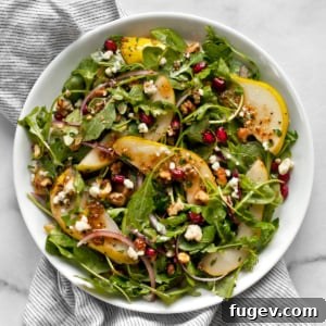 A vibrant pear salad with arugula and gorgonzola on a serving plate.