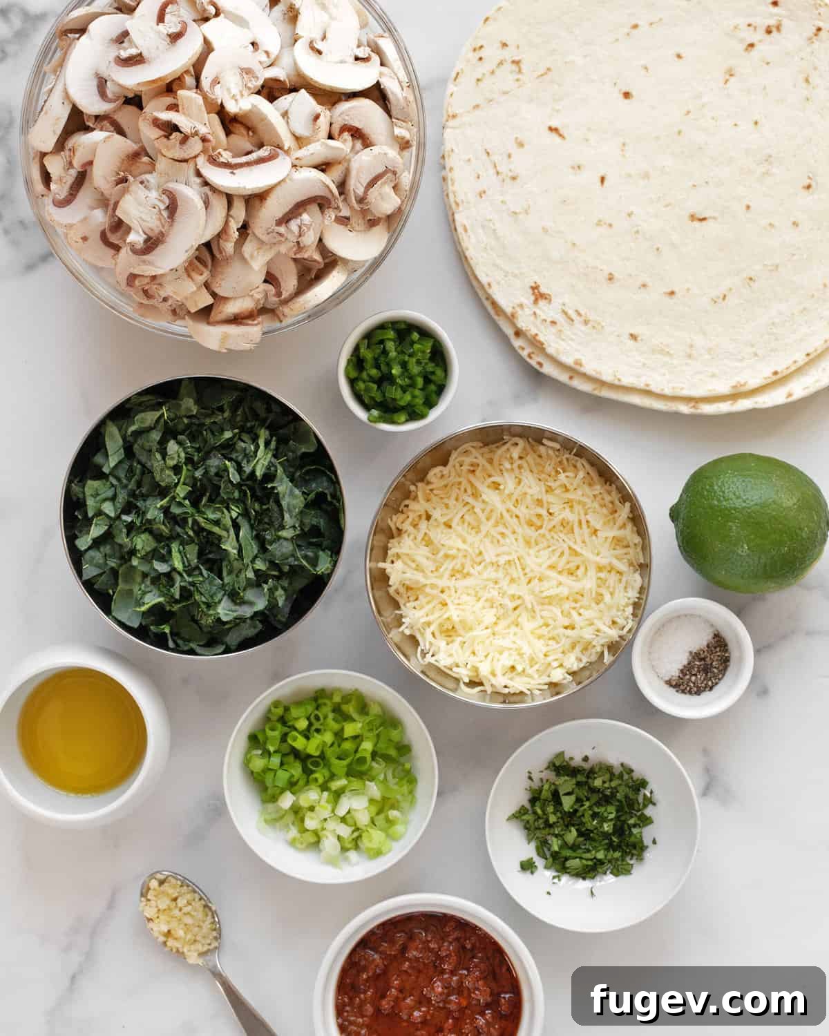 Golden Baked Mushroom Quesadillas 3 A beautiful arrangement of all the fresh ingredients needed for mushroom kale quesadillas: sliced mushrooms, kale leaves, jalapeños, garlic, scallions, cilantro, lime, tortillas, and shredded cheese.