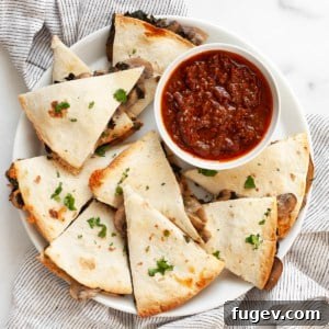 Sheet pan mushroom quesadillas on a plate with salsa, ready to be served.