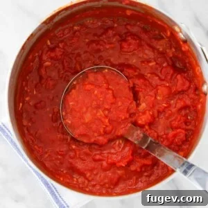 Close-up of a pot of vibrant red pasta sauce, highlighting its rich texture and color, indicative of a quick yet flavorful meal.