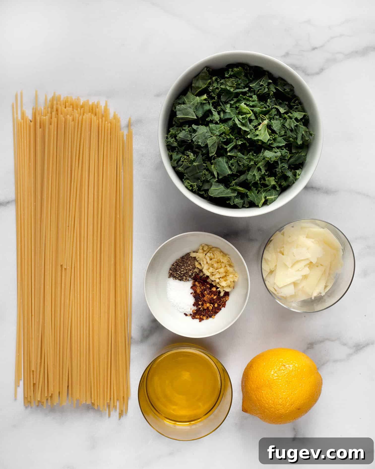 Zesty Lemon Pepper Pasta 3 A flat lay photograph showcasing the fresh ingredients for lemon pepper pasta including spaghetti, vibrant kale, bright lemons, garlic cloves, olive oil, and various spices.