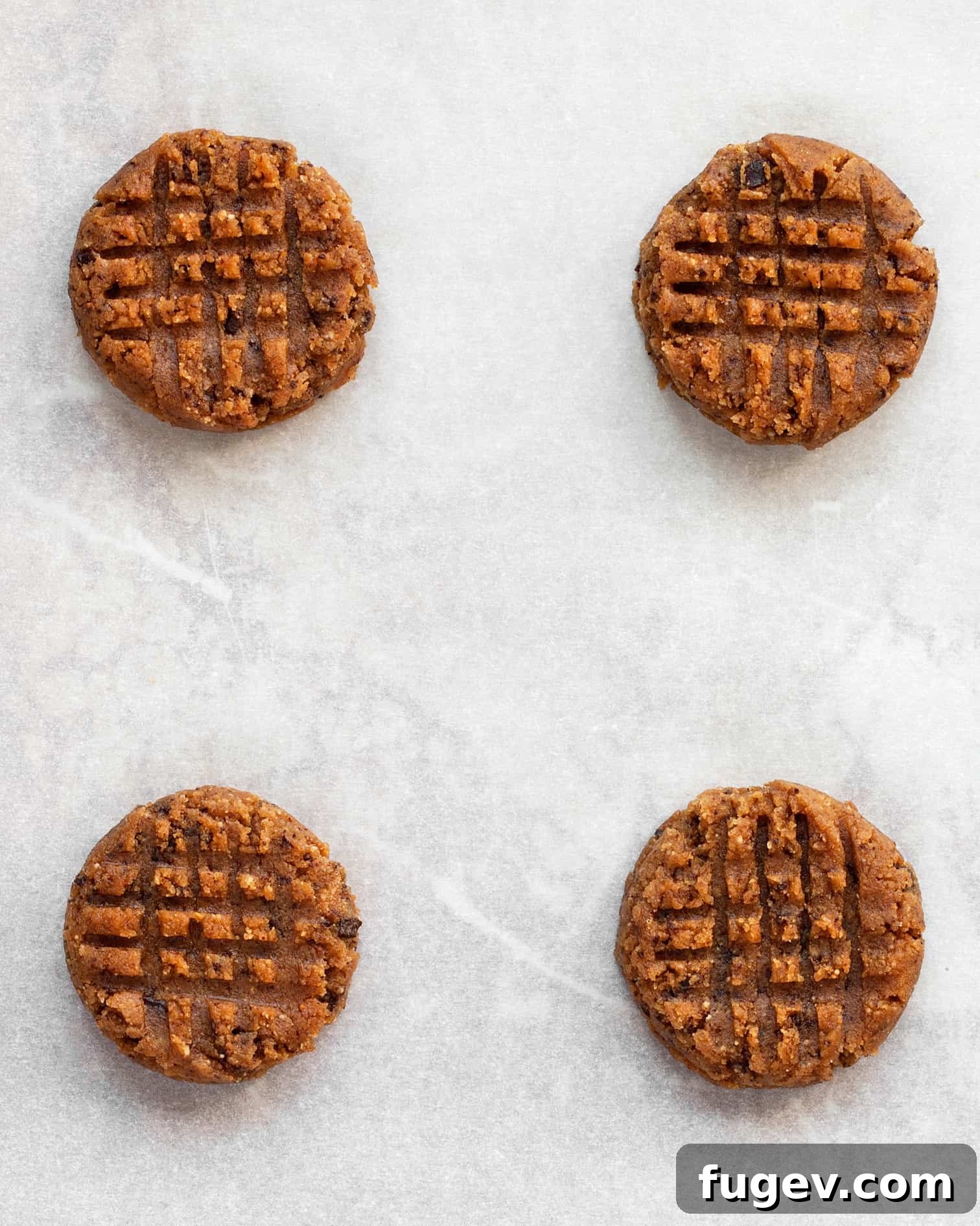 Decadent Peanut Butter Chocolate Chews 6 Peanut butter cookie dough balls individually shaped with a distinct crosshatch pattern pressed into their tops before baking.
