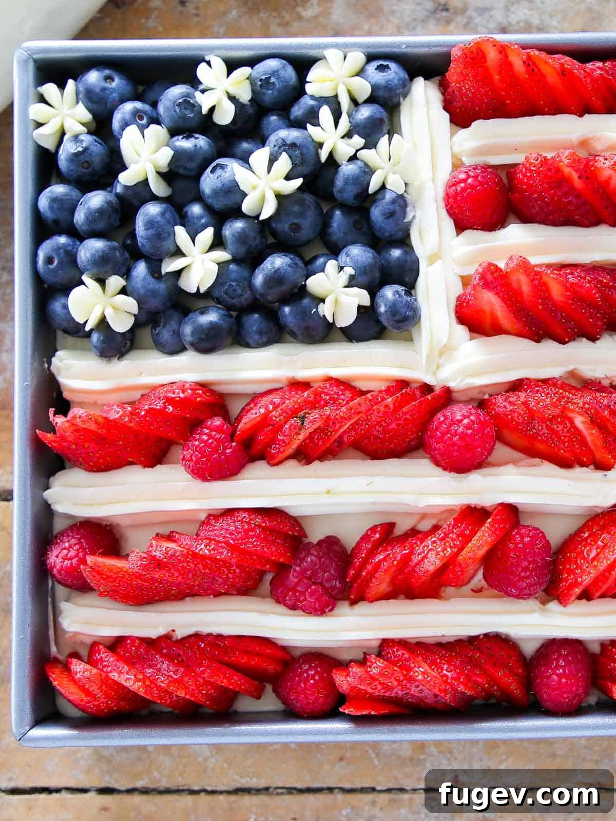 Stars Stripes and Sweetness 2 A stunning American Flag Cake, unsliced, showcasing vibrant red strawberries, blue blueberries, and white buttercream stripes, perfect for July 4th.