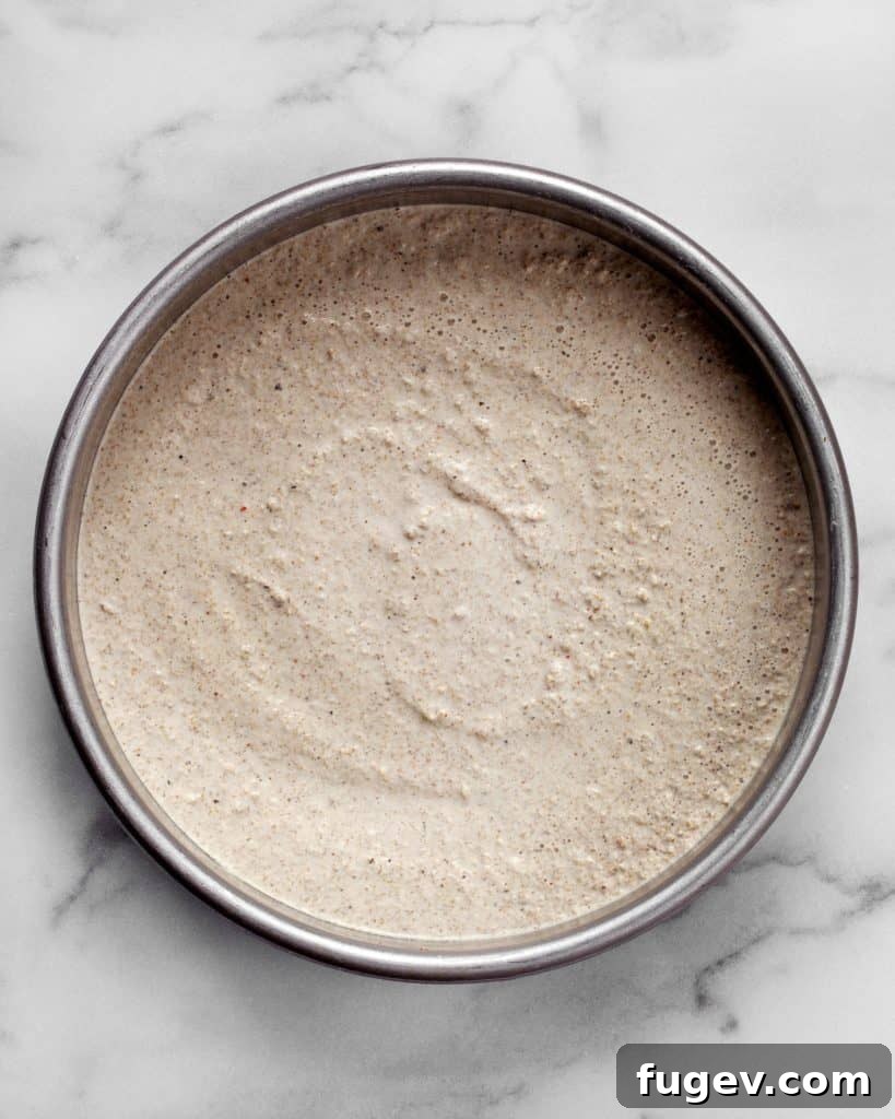 Nutrient-Packed Quinoa Crust 6 Quinoa pizza crust batter poured into a round cake pan, ready for baking.