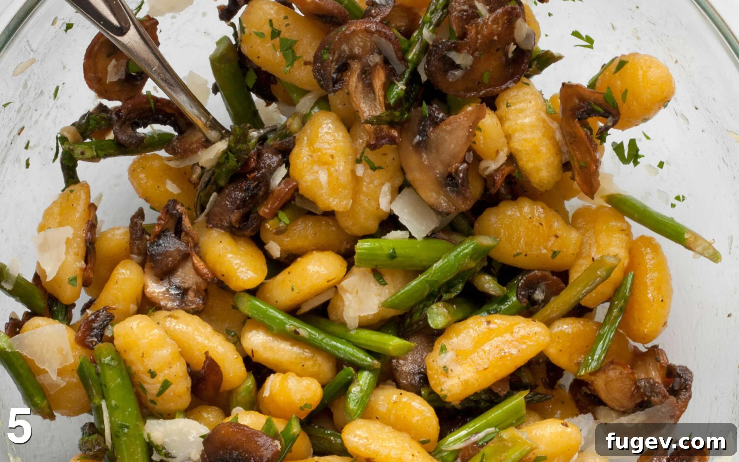 Garden Gnocchi Sheet Pan Feast 6 A bowl of roasted gnocchi, mushrooms, and asparagus, with fresh parsley and shaved Parmesan cheese folded in, ready to be served.