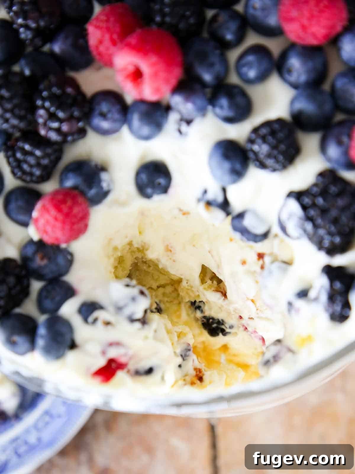 Summer Berry Dream 2 Top view of a trifle dish generously filled with vibrant berries, a portion scooped out.