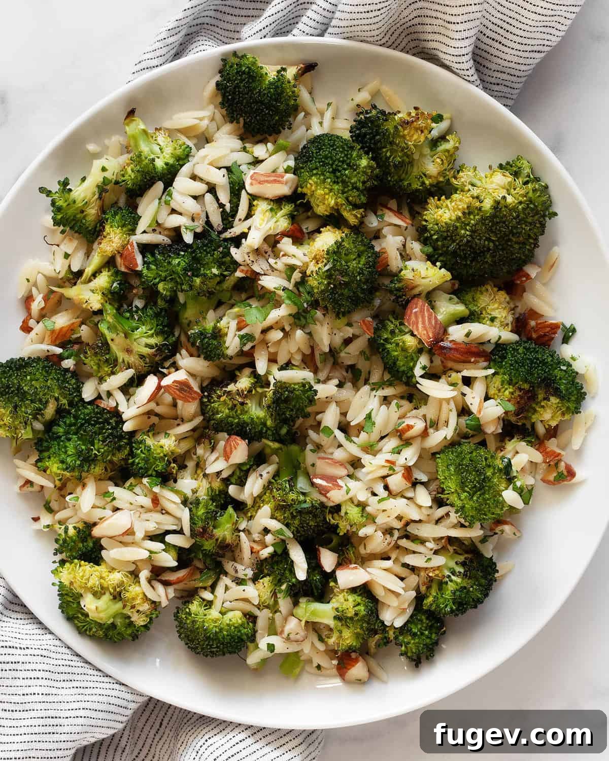 Golden Roasted Broccoli Orzo 2 Orzo with roasted broccoli, almonds, lemon and garlic on a plate, ready to be enjoyed.