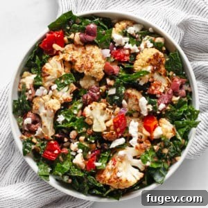 Kale salad with roasted cauliflower, tomatoes, and olives in a bowl.