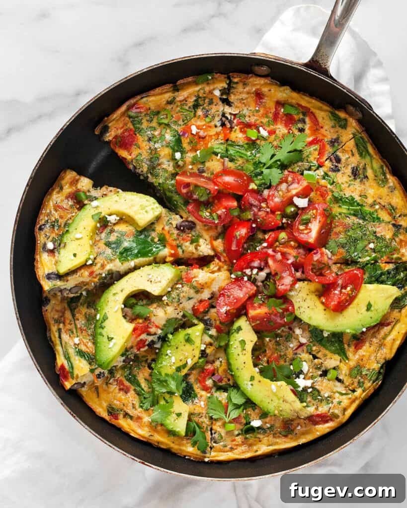 Hearty Roasted Pepper and Black Bean Frittata 5 A generously topped slice of Black Bean Roasted Pepper Frittata, adorned with a colorful medley of fresh cherry tomatoes, vibrant cilantro, and creamy avocado slices, highlighting its fresh appeal.