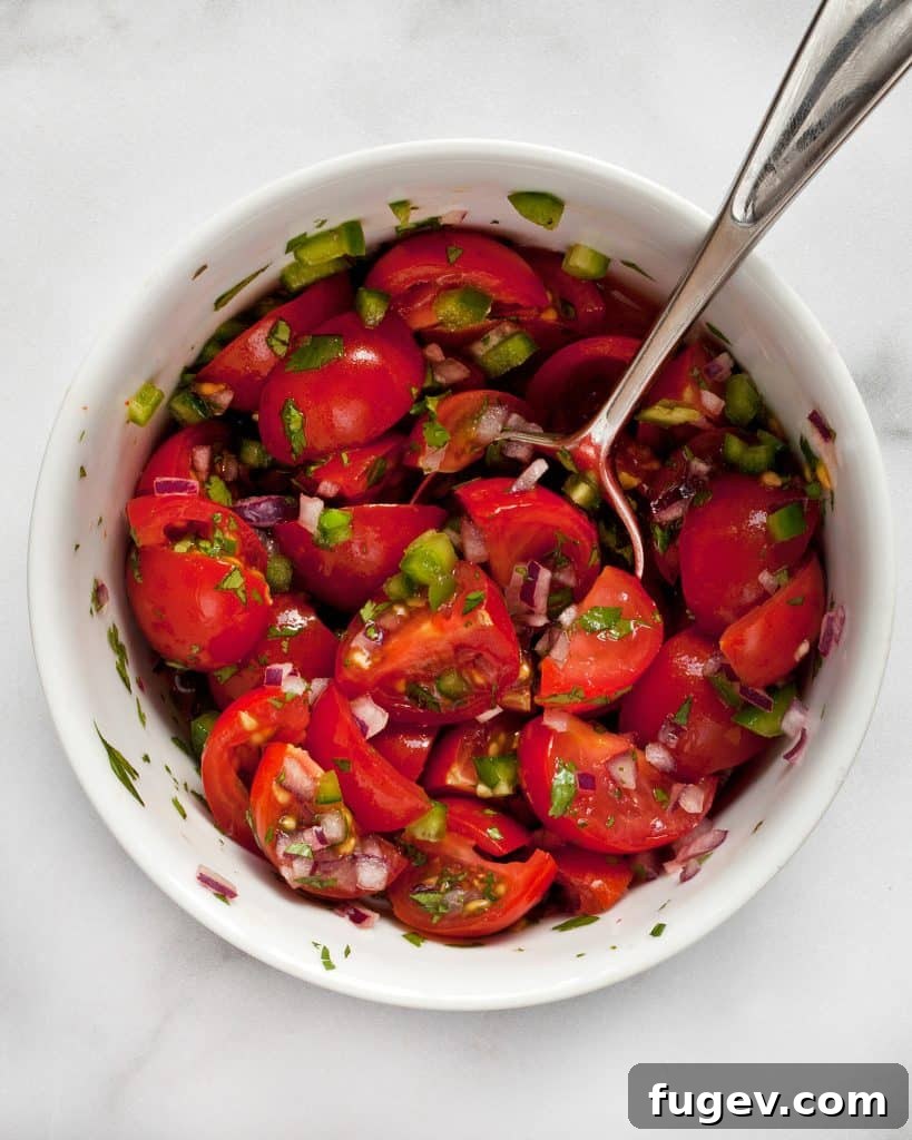 Hearty Roasted Pepper and Black Bean Frittata 8 A close-up view of cherry tomatoes, red onions, and jalapenos being stirred together in a bowl, forming a fresh and vibrant pico de gallo.